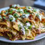 Cheesy nachos loaded with avocado, sour cream, and zesty toppings—perfect for game day snacking.  