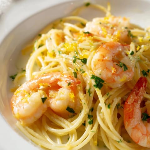 Sizzling garlic shrimp with fresh parsley garnish and lemon wedges on a plate for a bright dinner.
