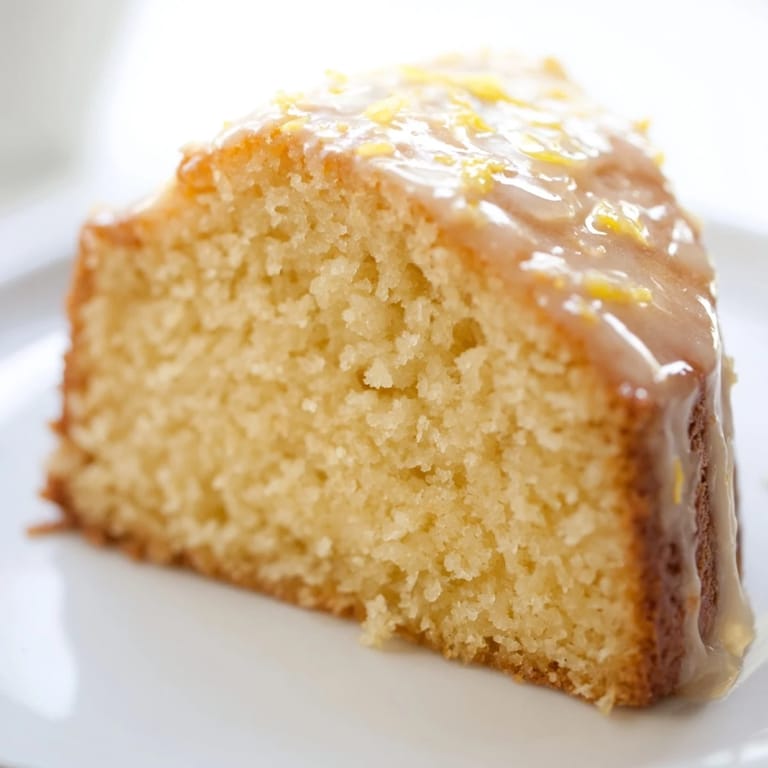 A beautiful slice of Lemon Pound Cake, moist and dense, with visible lemon zest throughout.