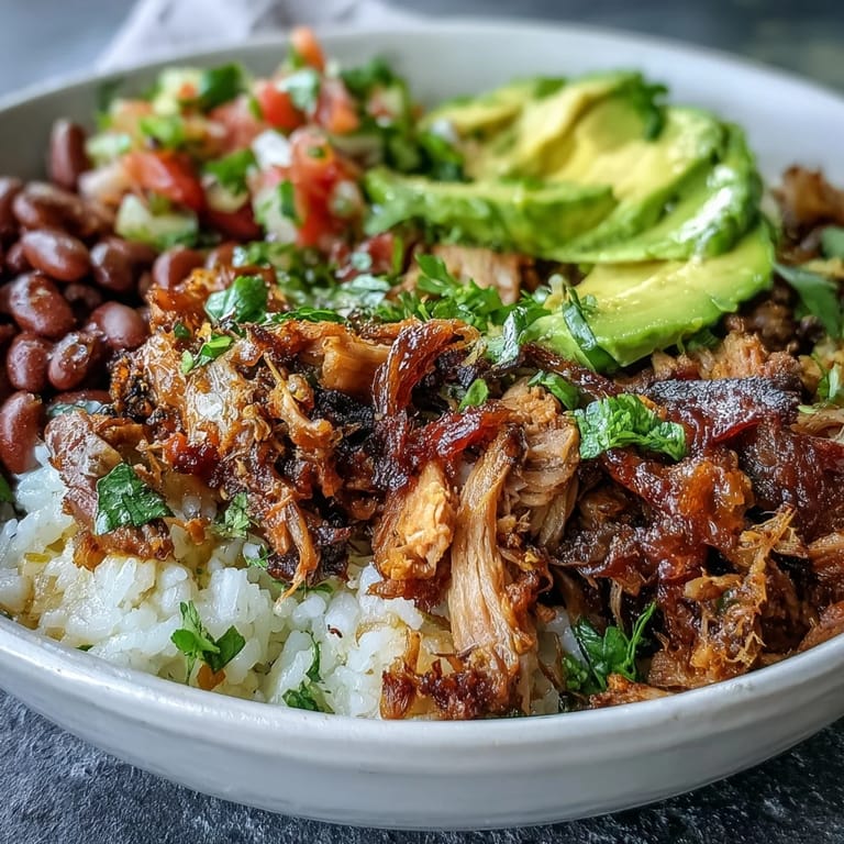 A close-up of a savory Carnitas Bowl garnished with cilantro and a side of lime wedges.